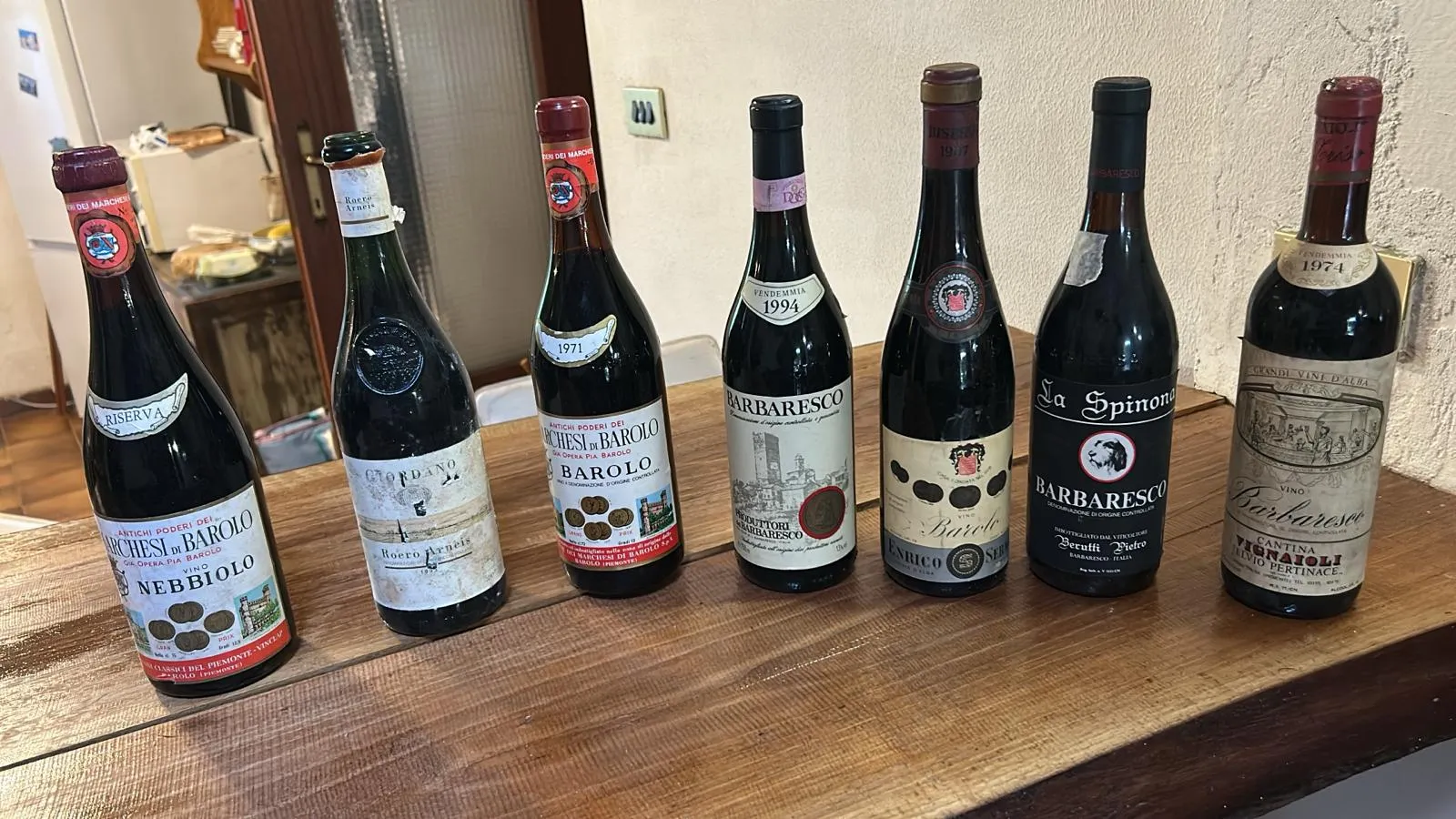 A line of vintage Barolo and Barbaresco bottles on the cellar table